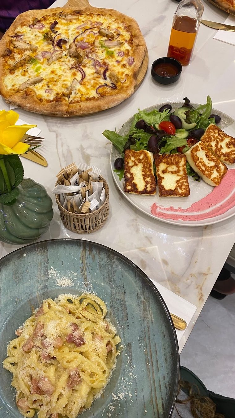 Pizza, halloumi salad and pasta set out on a table